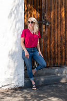 Female model in Gina v-neck pink blouse tucked in jeans outdoor on a sunny day.